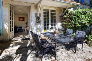 A patio with a table and chairs, a potted plant, and a view of a building with a garage door.
