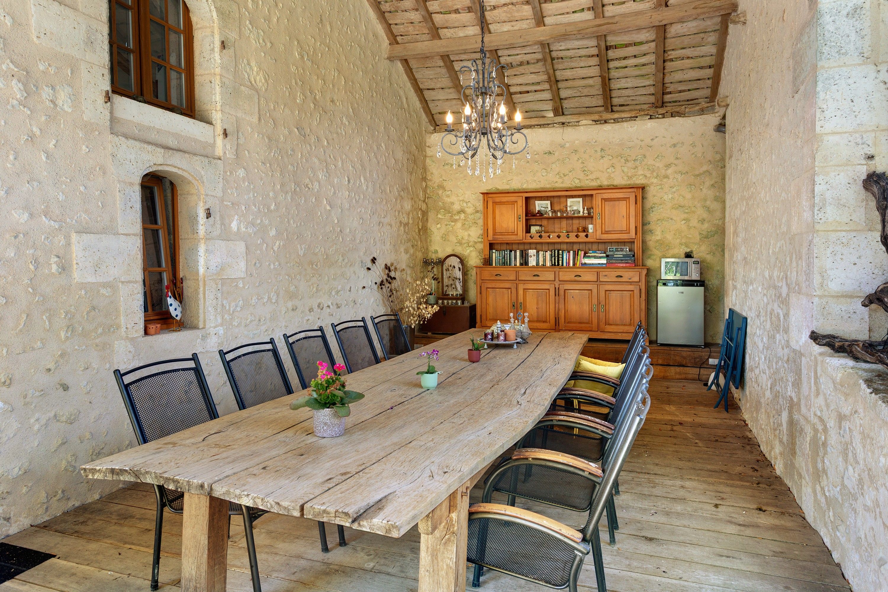 Un'accogliente sala da pranzo con un tavolo e sedie in legno, un lampadario e una cucina sullo sfondo.