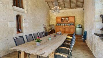 Un'accogliente sala da pranzo con un tavolo e sedie in legno, un lampadario e una cucina sullo sfondo.