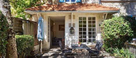 Un patio couvert avec des sièges d’extérieur, un mur en pierre et un espace jardin.