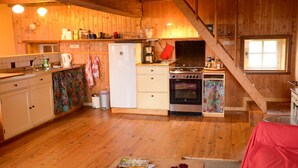 Een houten interieur met een keukenhoek, inclusief een koelkast, fornuis en kastjes.