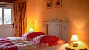 Een slaapkamer met een bed, twee bedlampen, een raam met gordijnen en een deur.