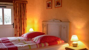 Ein Schlafzimmer mit einem Bett, zwei Nachttischlampen, einem Fenster mit Vorhängen und einer Tür.