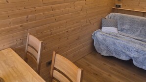 En trästuga med en inredning som består av ett matbord, stolar, en soffa och en inramad tavla på väggen.