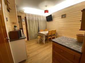 Eine kompakte Küche mit Essbereich, Holzwänden, einem Flachbildfernseher und einem kleinen Tisch.