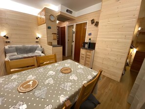 Ein gemütliches Zimmer mit einem Bett, einem Esstisch mit gemustertem Tischlaufschütz und Holzwänden.