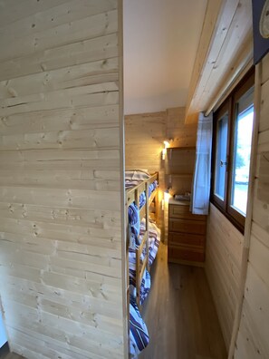 A narrow wooden corridor with bunk beds and a small kitchenette. - Studio “La Cachette De Marmotte & Myrtille” with Mountain View and Balcony (Fontcouverte-la-Toussuire)