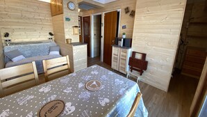 A cozy room with a bed, a dining table, and a kitchenette.