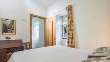 A bedroom with a bed, a dresser, a door, and a window with curtains.