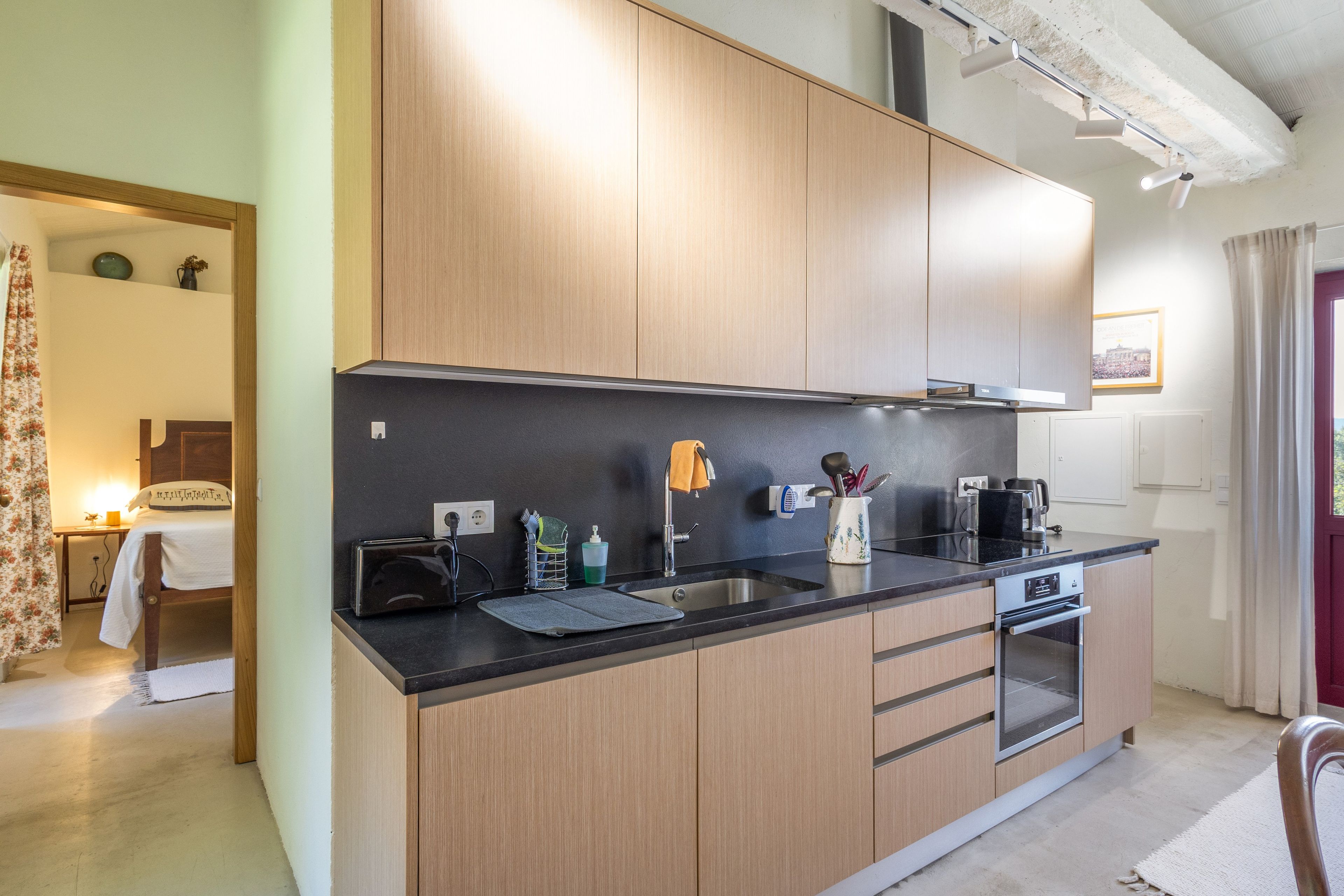 Een moderne keuken met houten kastjes, een zwart aanrecht en roestvrijstalen apparatuur.