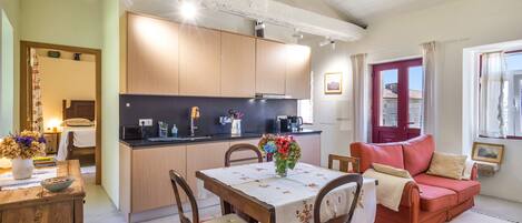 Un espacio habitable compacto con kitchenette, comedor y zona de estar.