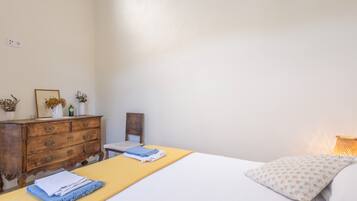 A bedroom with a bed, a wooden dresser, a chair, and a bedside table.