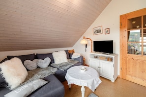 Un salon confortable avec un canapé, une petite table, un téléviseur et un meuble.