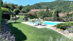 A backyard with a swimming pool, outdoor furniture, and a pergola.