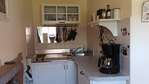 A kitchen with white cabinets, a coffee maker, and various utensils hanging above the sink. - Apartment 'Ca Di Buie' with Private Terrace, Garden, Pool and Wi-Fi (Monastero Bormida)