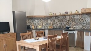 Una cocina compacta con una mesa de comedor, sillas, refrigerador, estufa y lavaplatos.