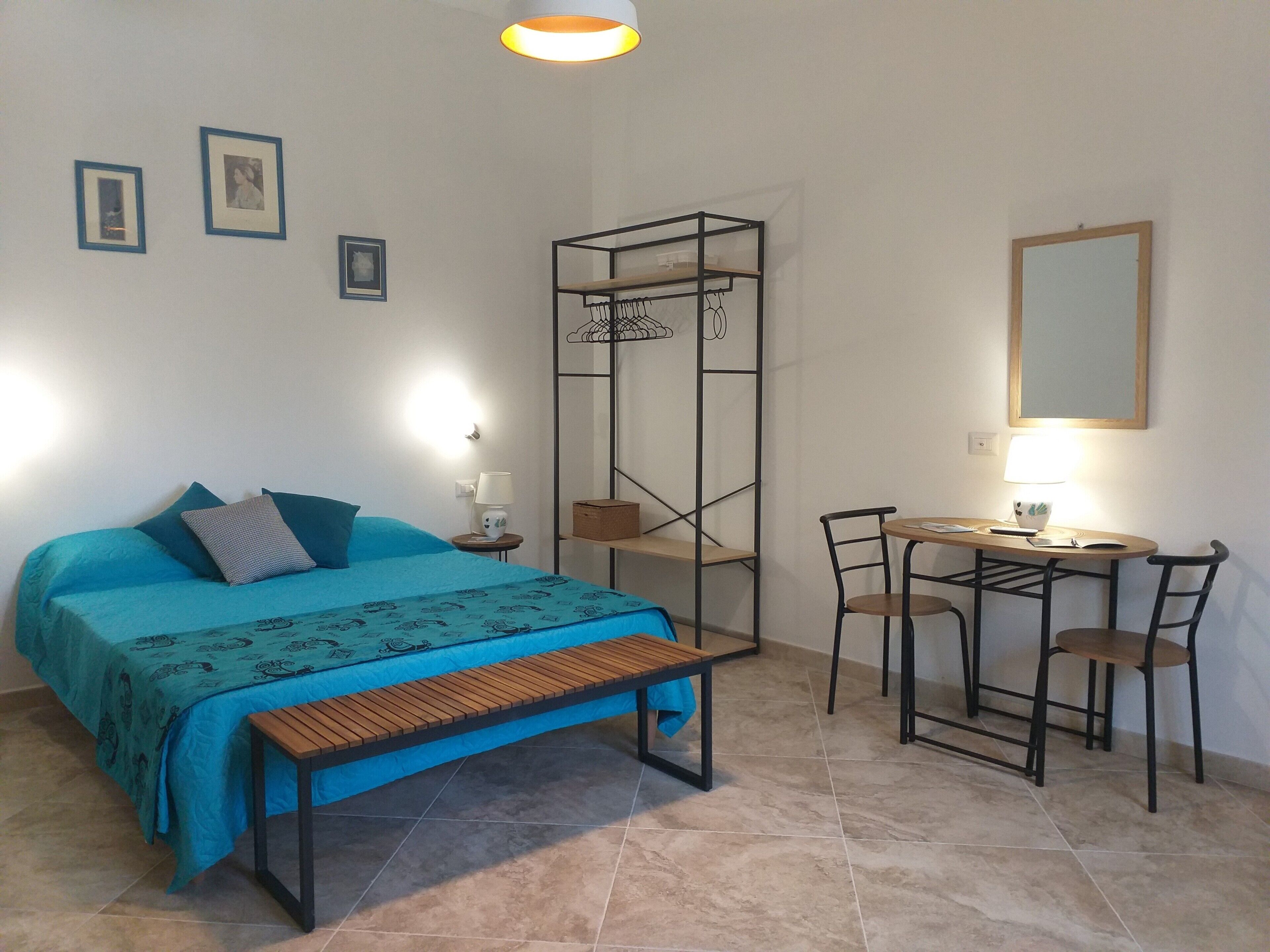 Une chambre à coucher comprenant un lit, une table de chevet, une lampe et un bureau avec des chaises.