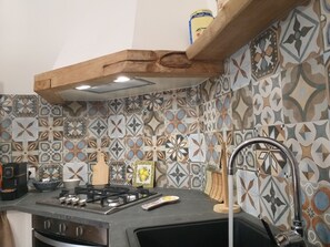 A kitchen with a gas stove, a sink, and a patterned backsplash.
