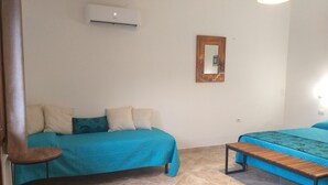 Una habitación con dos camas, una mesita, un aire acondicionado y un espejo en la pared.