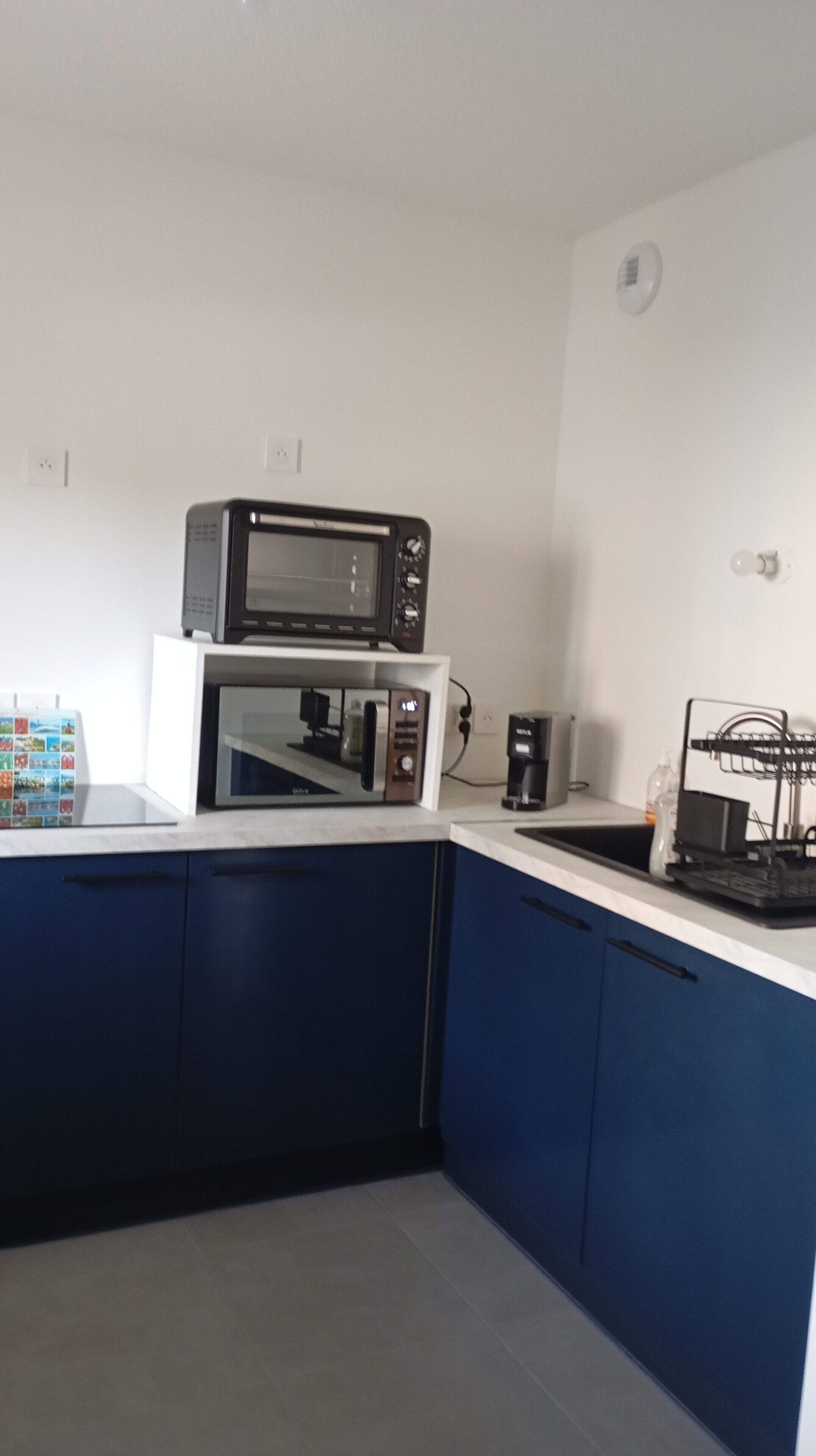 Eine Küche mit Mikrowelle, Kaffeemaschine und kleinem Kühlschrank.