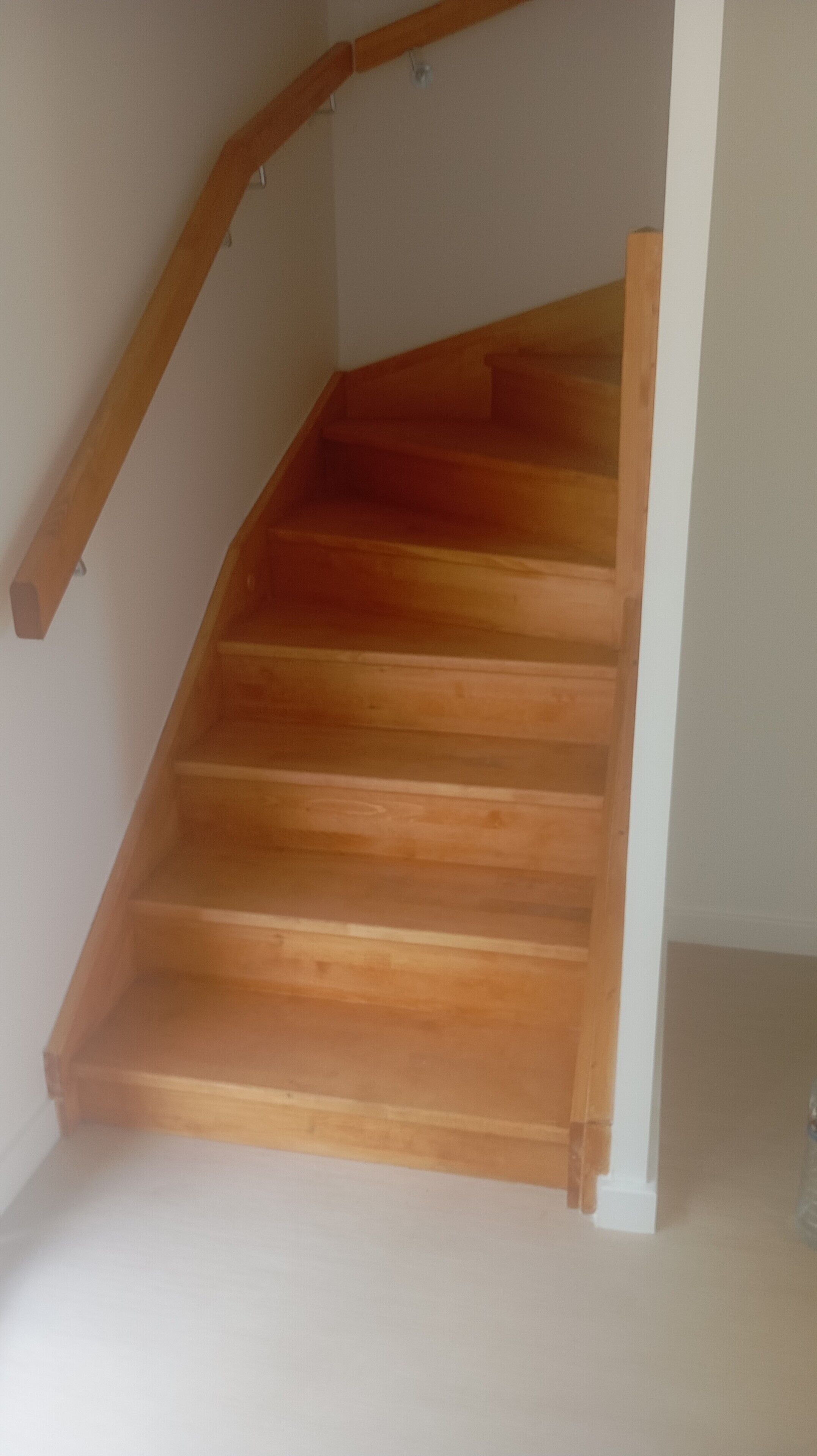 Un escalier en bois, doté d’une rampe et d’un palier.