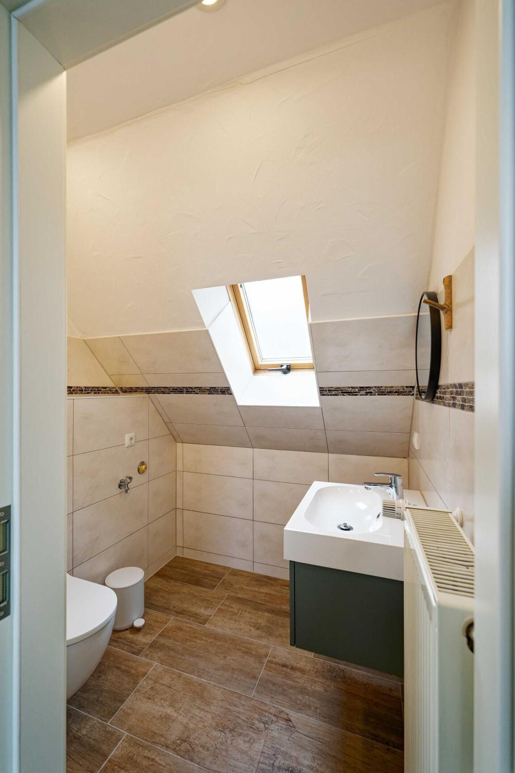 Un bagno compatto con finestra a lucernario, un water e un lavandino.