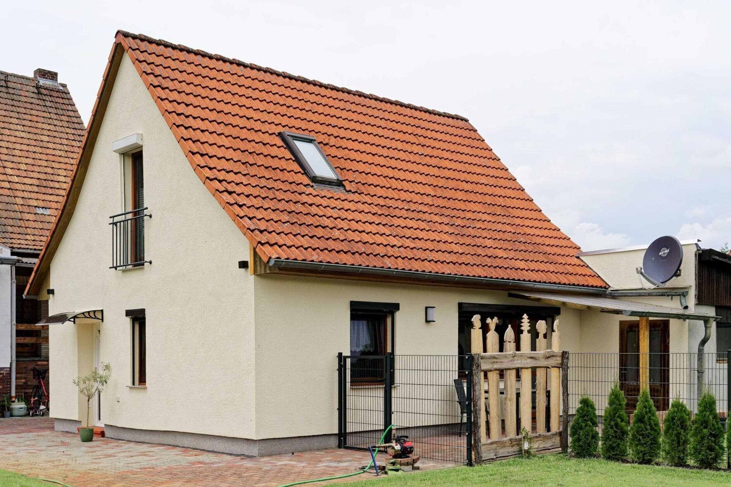 A two-story house with a sloped red-tiled roof, a small window, and a satellite dish.