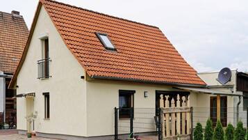 A two-story house with a sloped red-tiled roof, a small window, and a satellite dish.