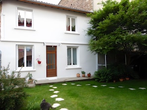 A two-story house with a front door, windows, and a small garden with stepping stones.