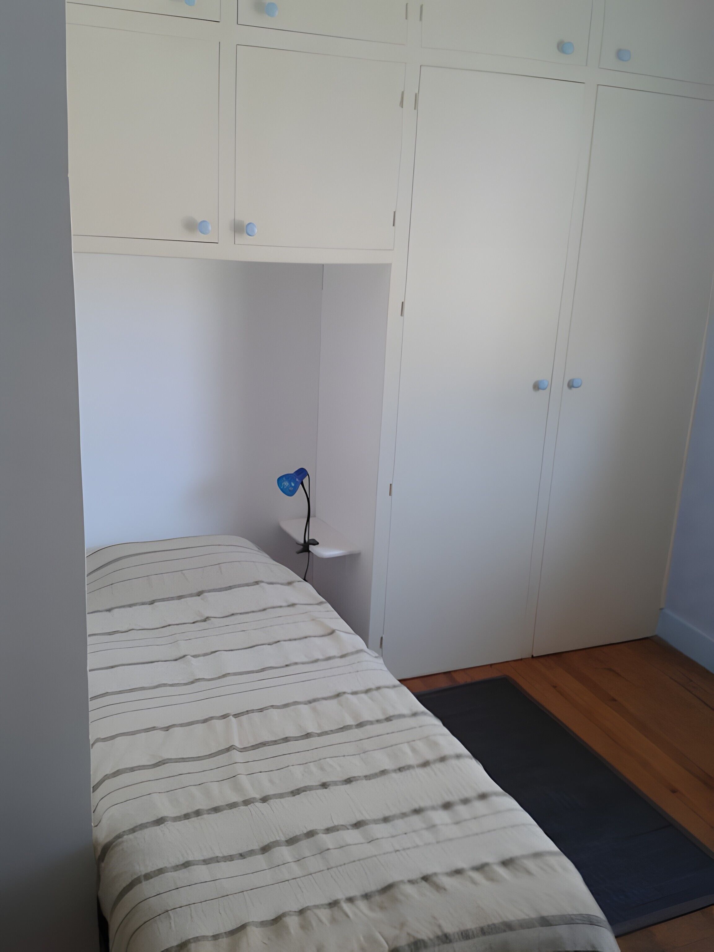 Une chambre à coucher avec un lit, une table de chevet, une lampe et une armoire.