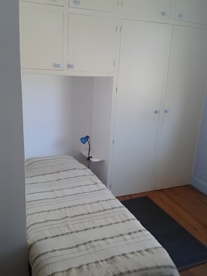A bedroom with a bed, a bedside table, a lamp, and a wardrobe.