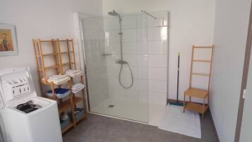 Ein Badezimmer mit einer gläsernen Dusche, einem weißen Waschbecken und einem Holzbodenregal.