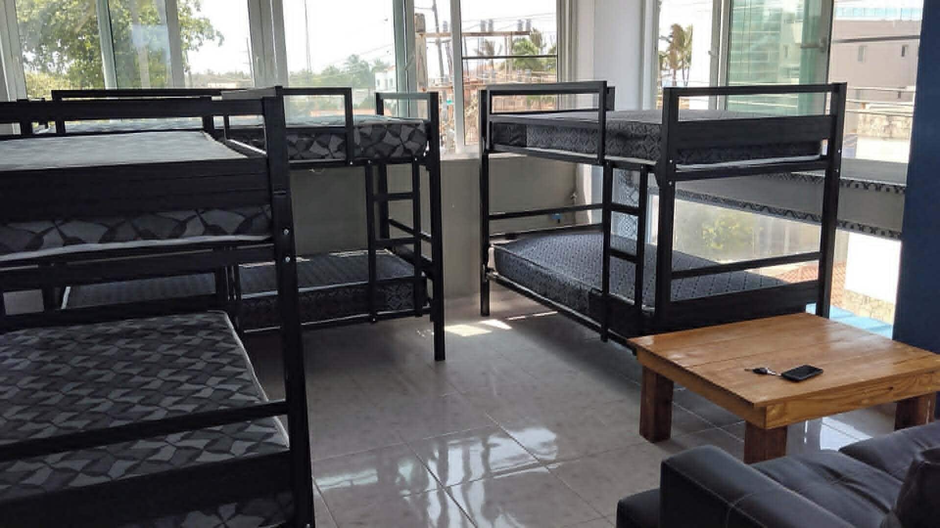 Bunk beds with a wooden table and a couch in a room with large windows.