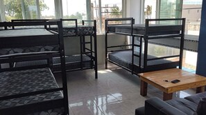 Bunk beds with a wooden table and a couch in a room with large windows.