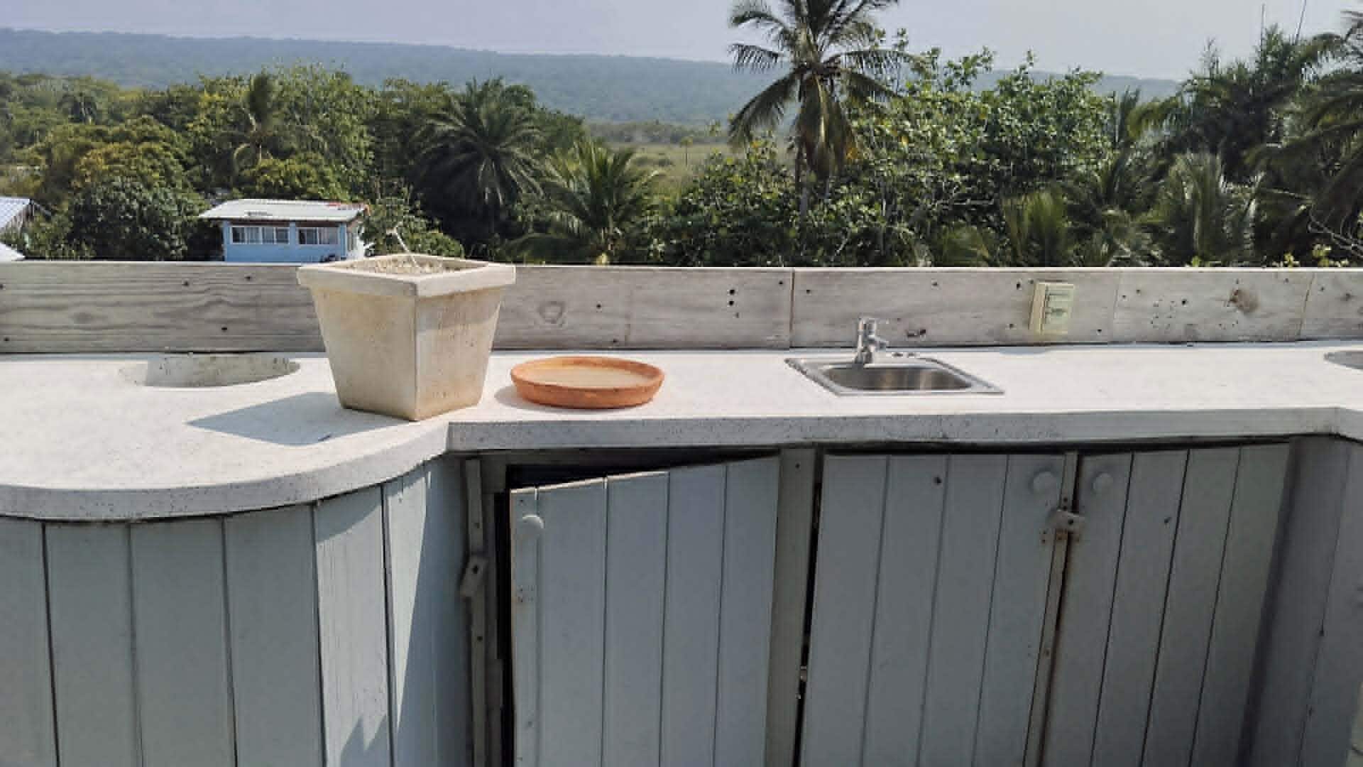 A rooftop with a concrete sink, a small bowl, and a wooden structure.