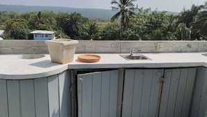 Una azotea con un lavabo de concreto, un cuenco pequeño y una estructura de madera.