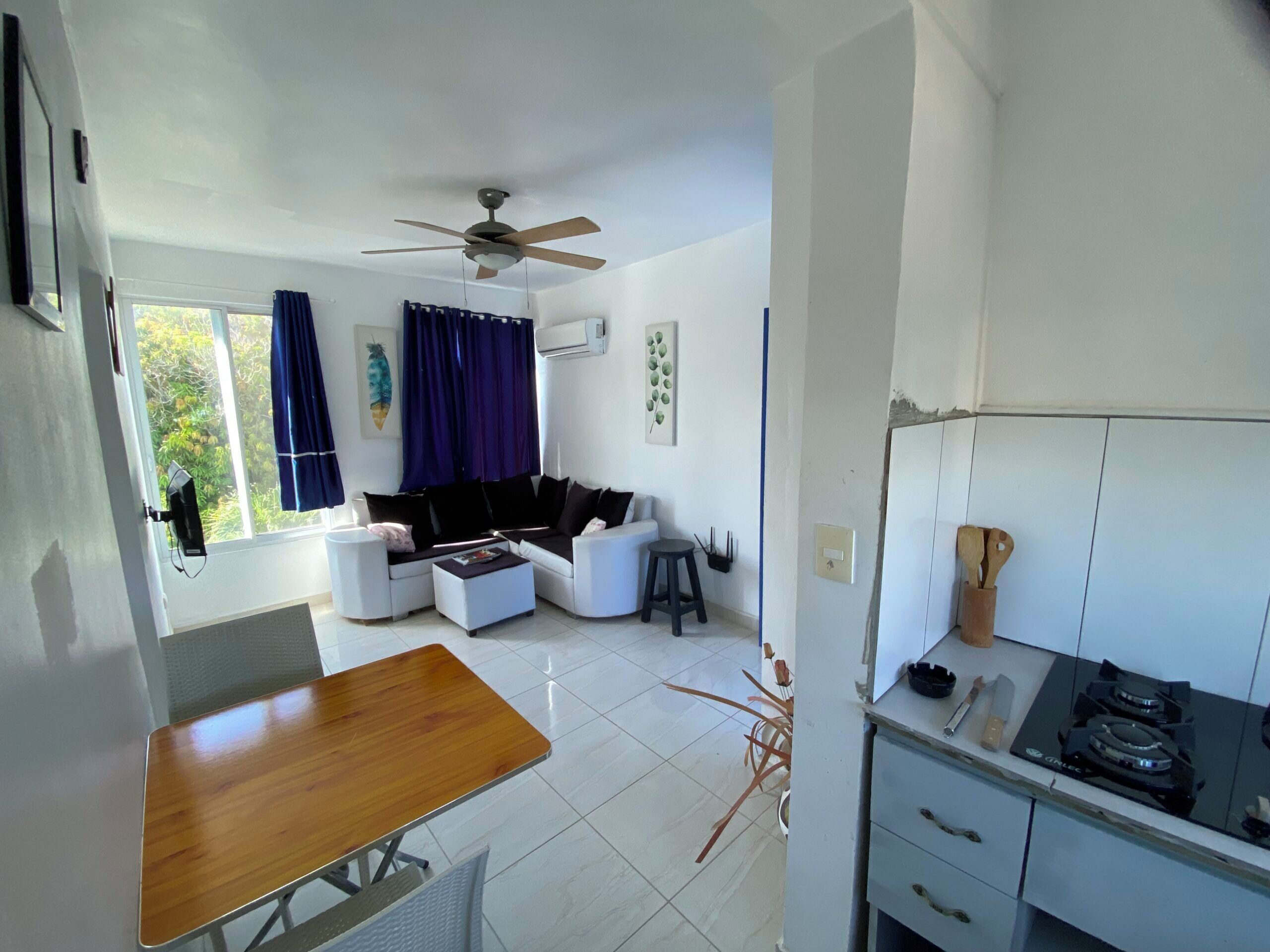 Una sala moderna con sofá, una mesa de centro, una mesa de comedor y una zona de cocina con estufa.
