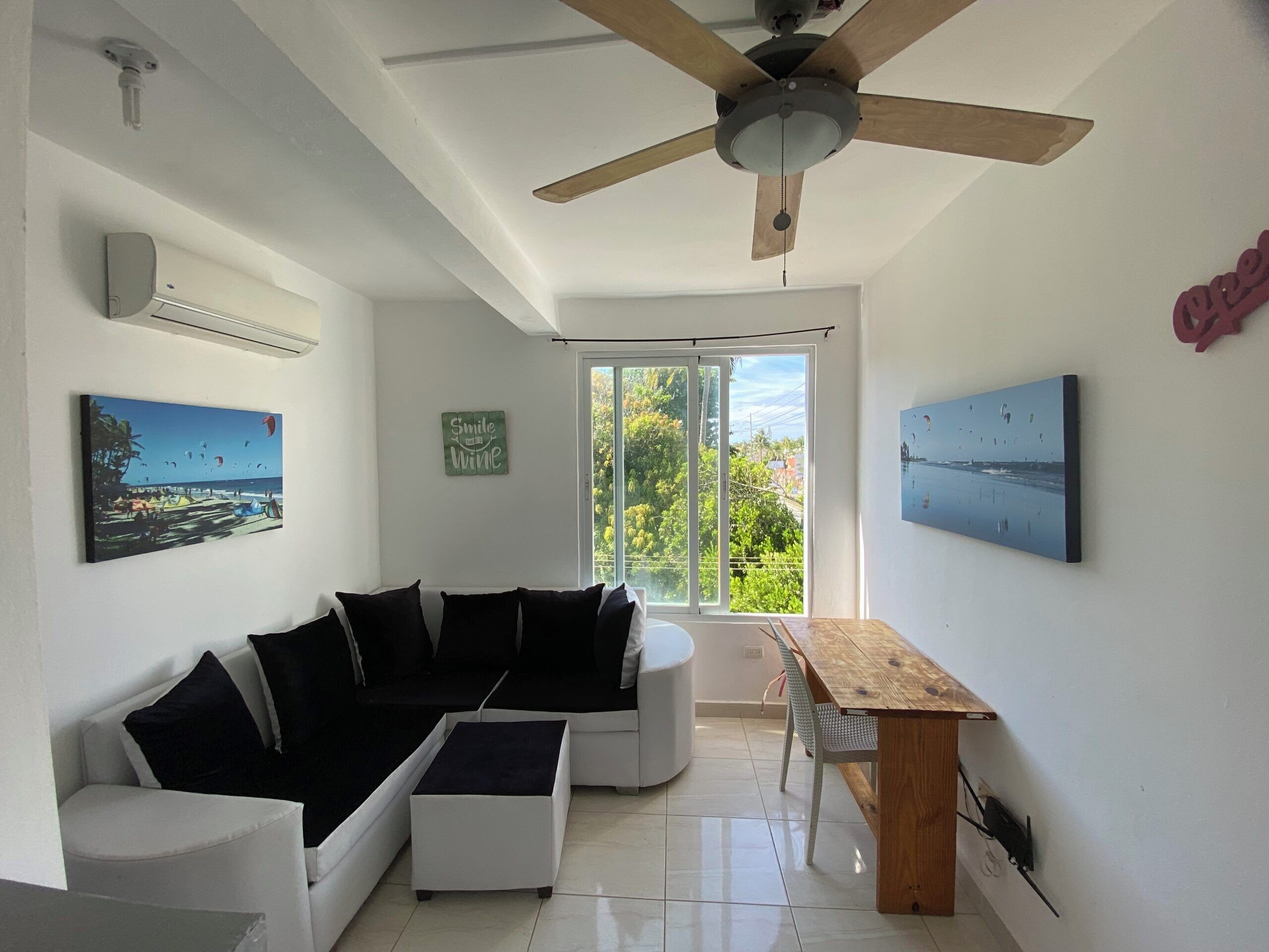 Una sala moderna con un sofá modular, una mesa de comedor de madera y un ventilador de techo.