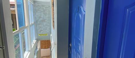 A hallway with a blue door, a staircase, and a view of the outside.