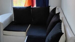 Una habitación con un sofá blanco, una ventana con cortinas y un ventilador de techo.