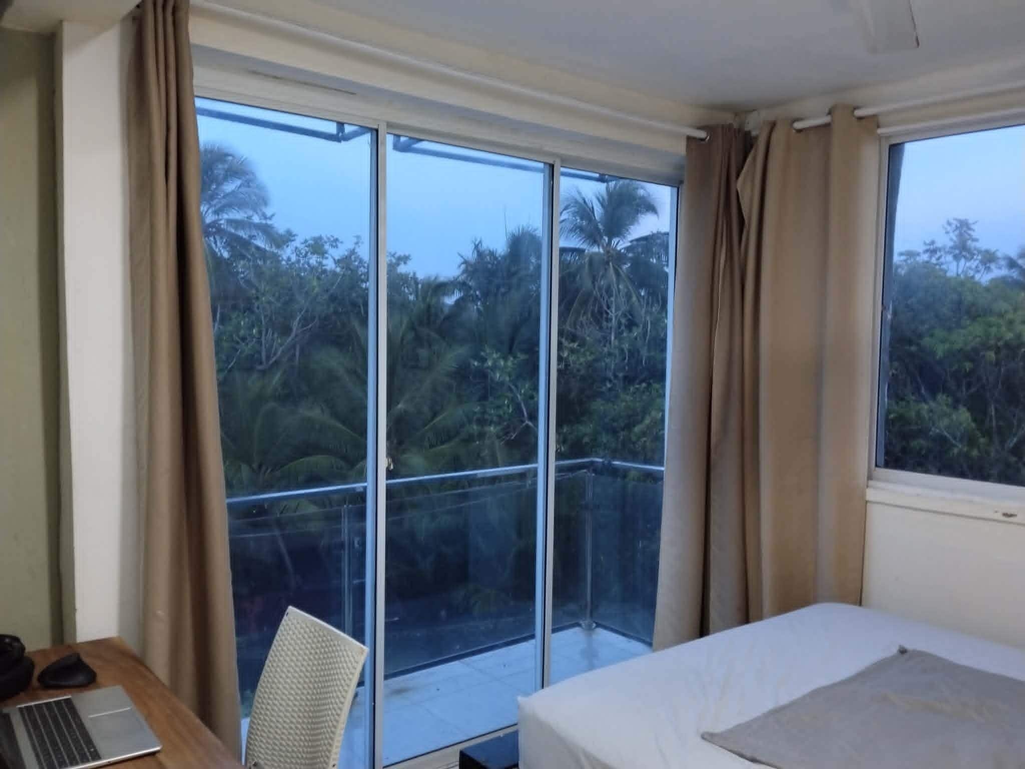 A room with a bed, a desk with a laptop, and a chair.