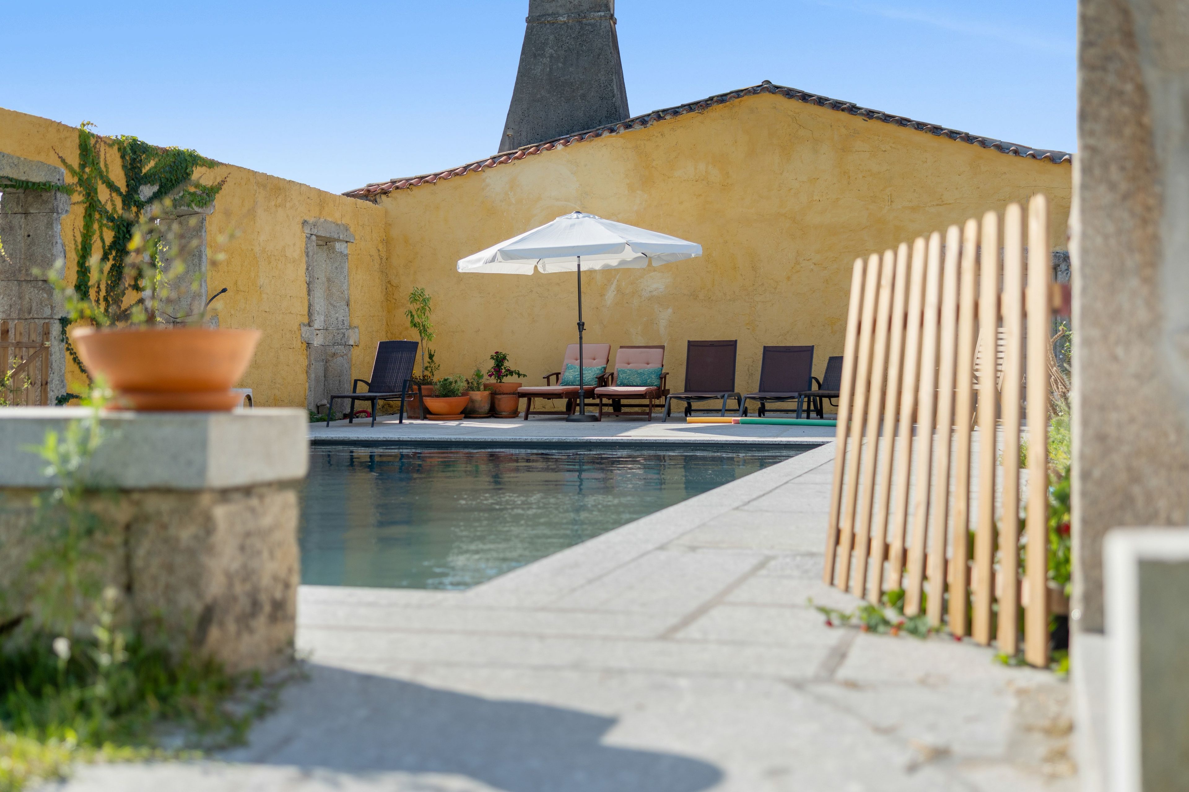 Un espace piscine avec des chaises longues et un parasol.