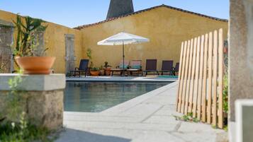 Un espace piscine avec des chaises longues et un parasol.