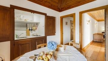Un'area pranzo con tavolo apparecchiato, una cucina con mobili in legno e un corridoio che porta a un'altra stanza.