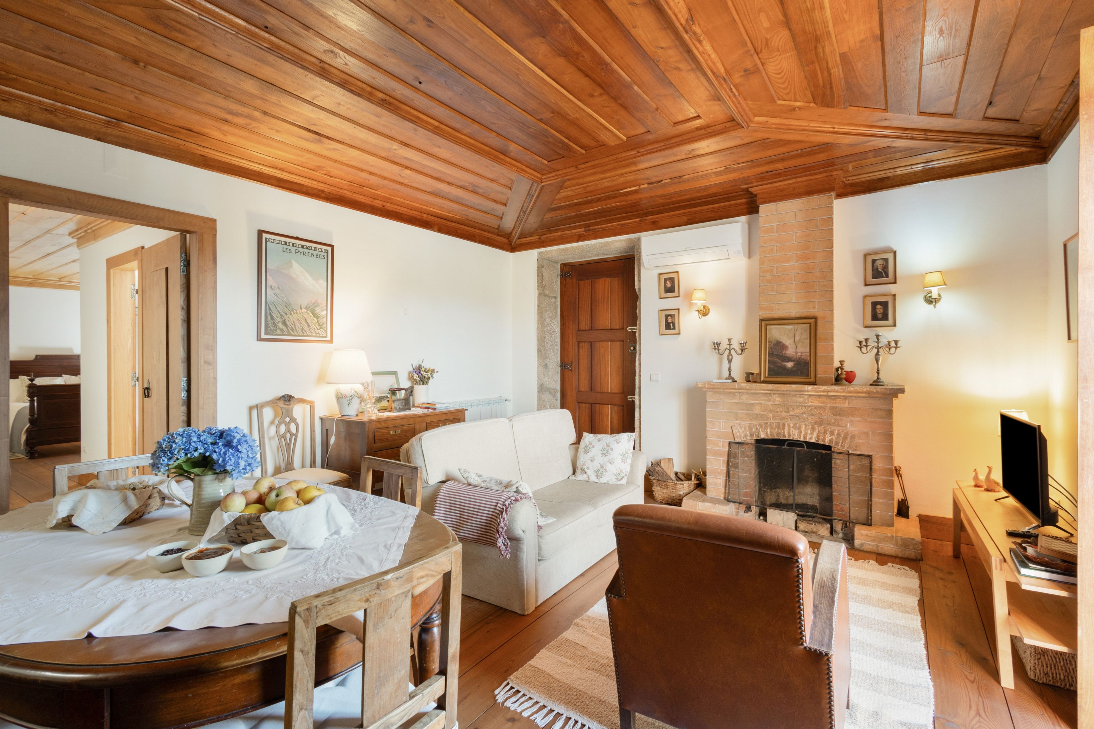Un accogliente soggiorno con camino, soffitto in legno e zona pranzo con tavolo apparecchiato per un pasto.