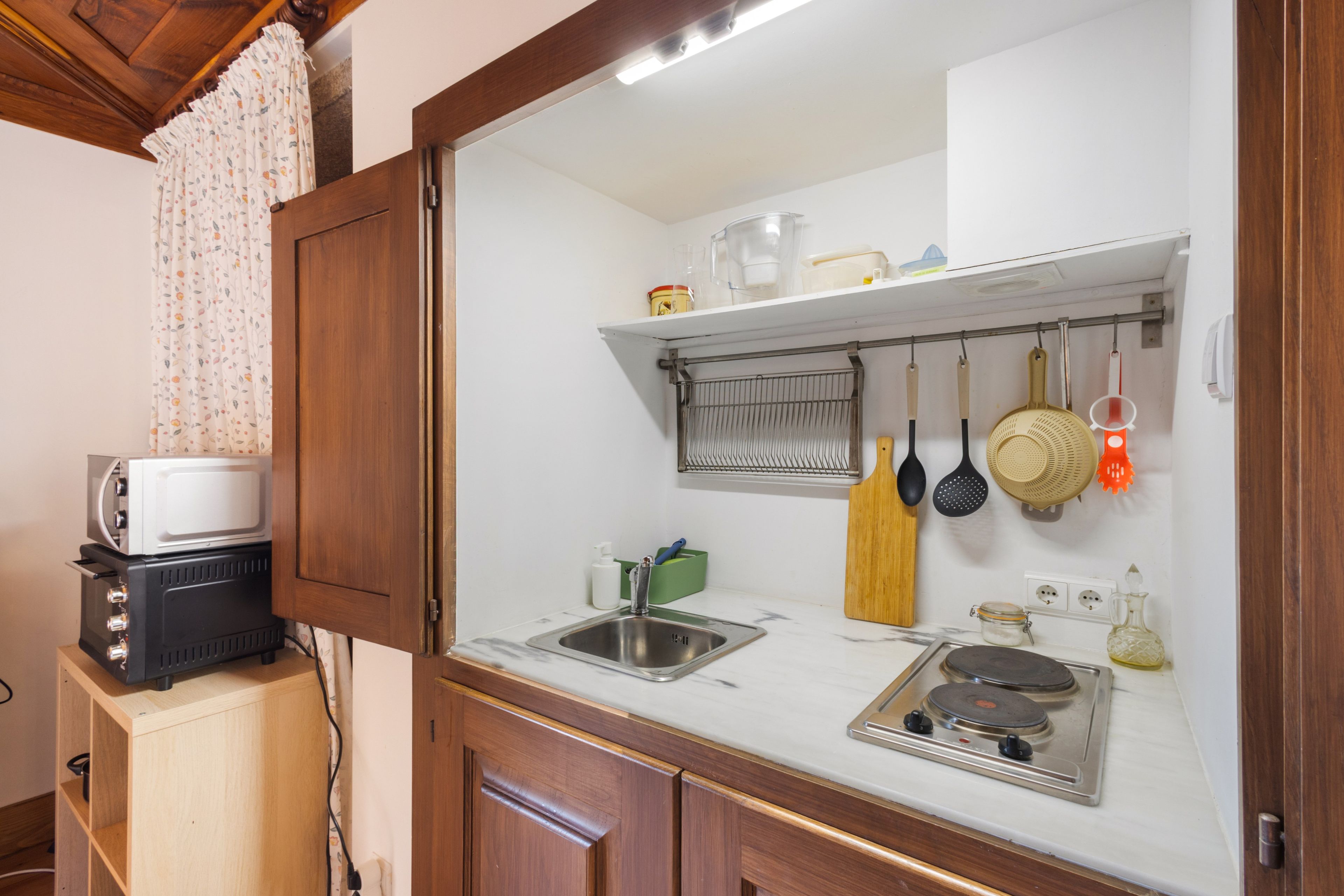 Una cucina compatta con forno a microonde, lavello e piano cottura.