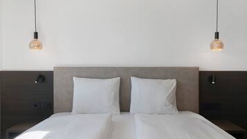 A double bed with white bedding, two bedside tables, and two wall-mounted lamps.