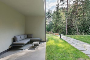 Ein moderner Sitzbereich im Freien mit integriertem Sitzplatz und einem kleinen Tisch, neben einem Gebäude mit schlichter Wand.
