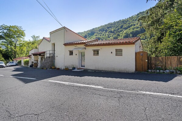 A two-story building with a tiled roof, a front entrance, and a driveway.
