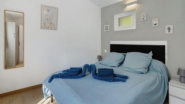 A bedroom with a bed, a bedside table, a lamp, and wall-mounted pictures.